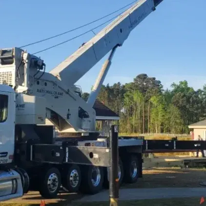 Rough terrain crane lifting steel beams on muddy ground