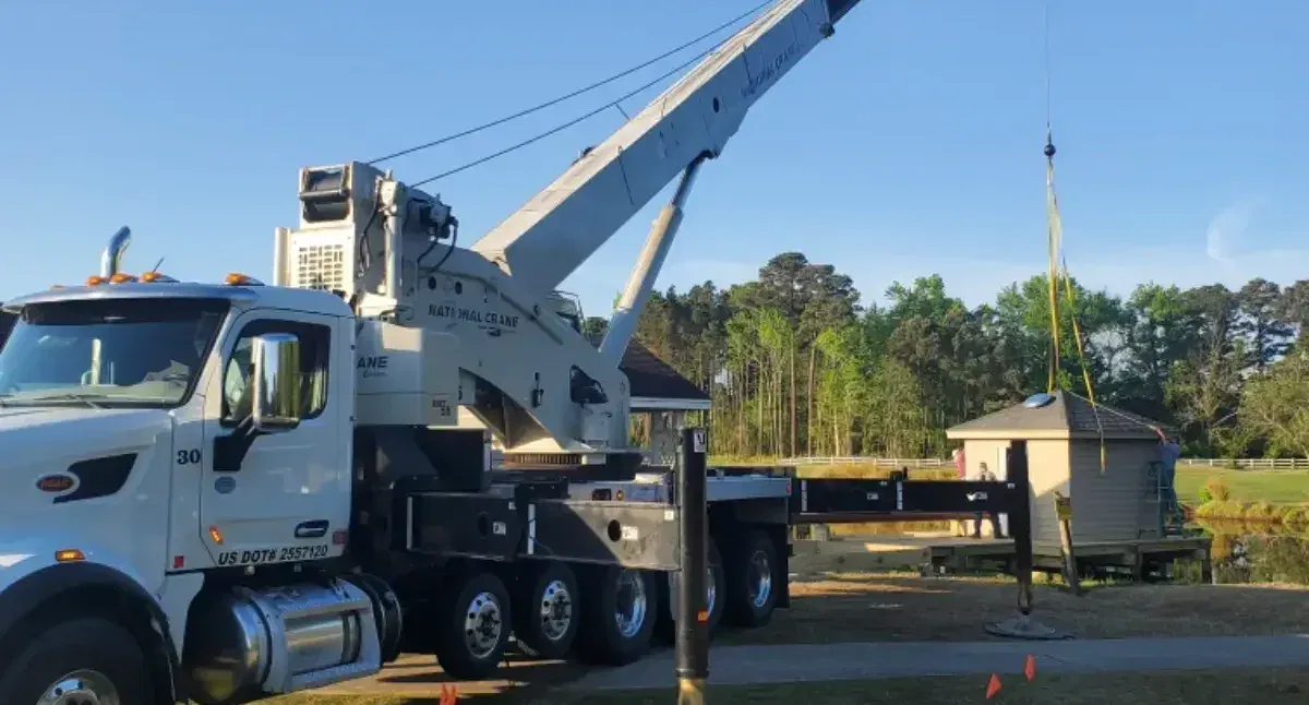 Rough terrain crane lifting steel beams on muddy ground