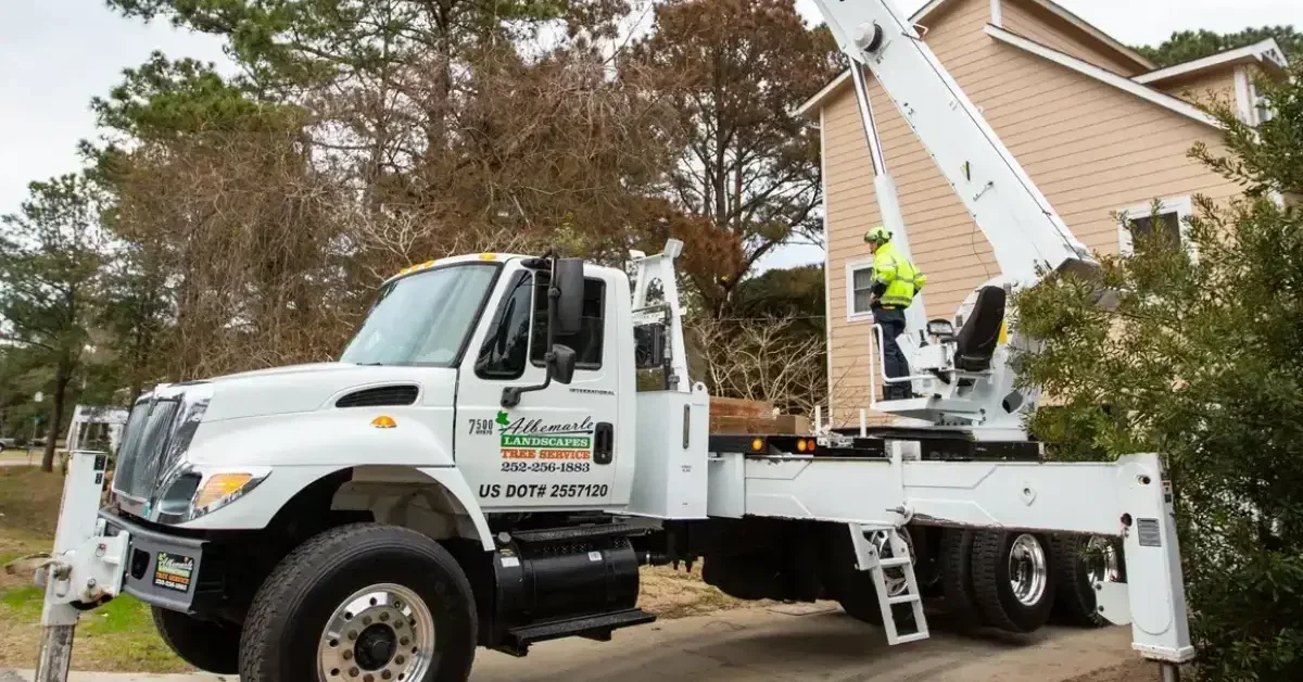 Crane truck lifting roof shingles onto a multi-level OBX beach house