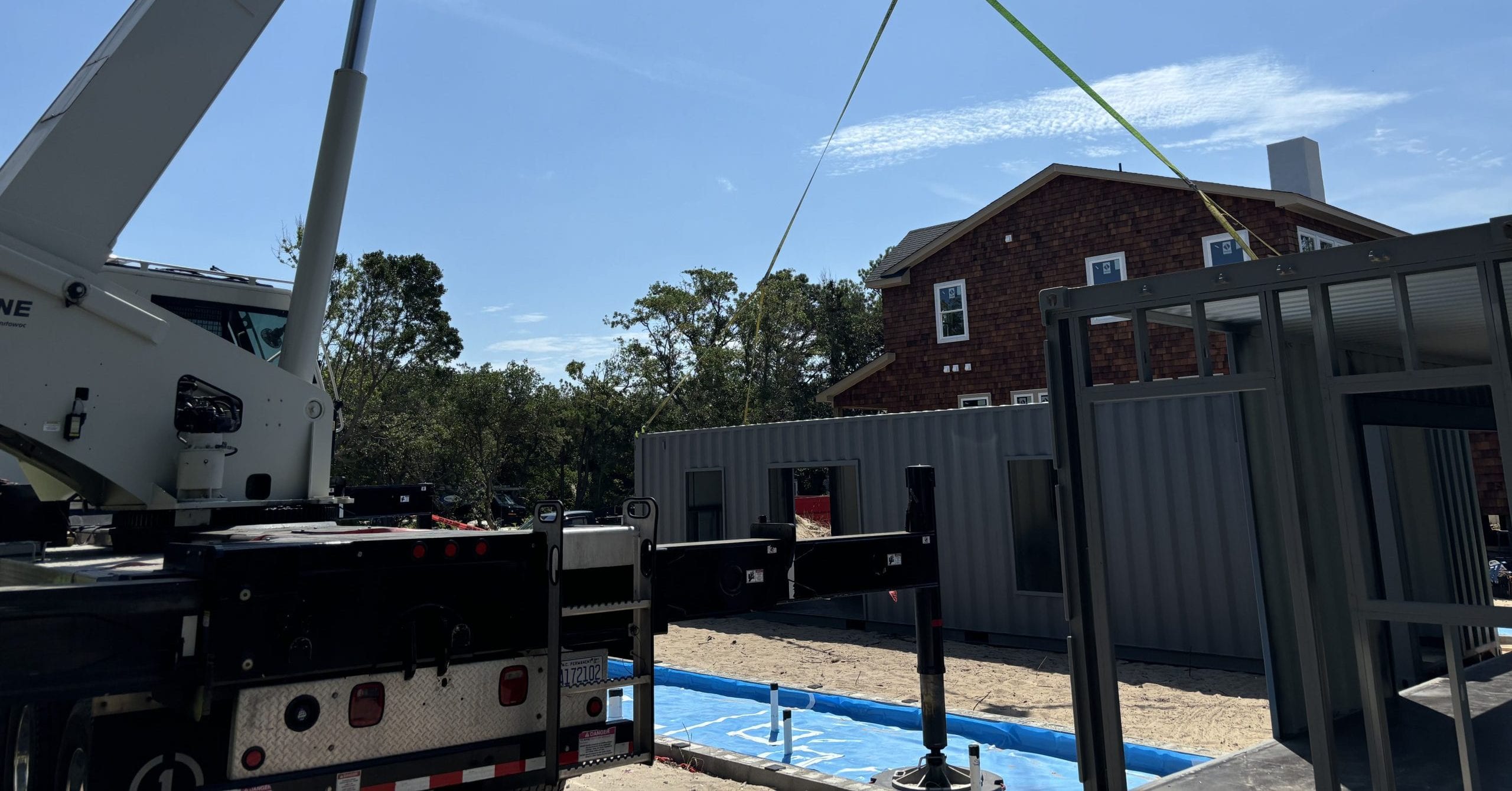 Crane lifting HVAC unit onto a commercial building in coastal construction zone