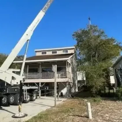 Residential boom truck lifting HVAC equipment at a home in Dare County, NC