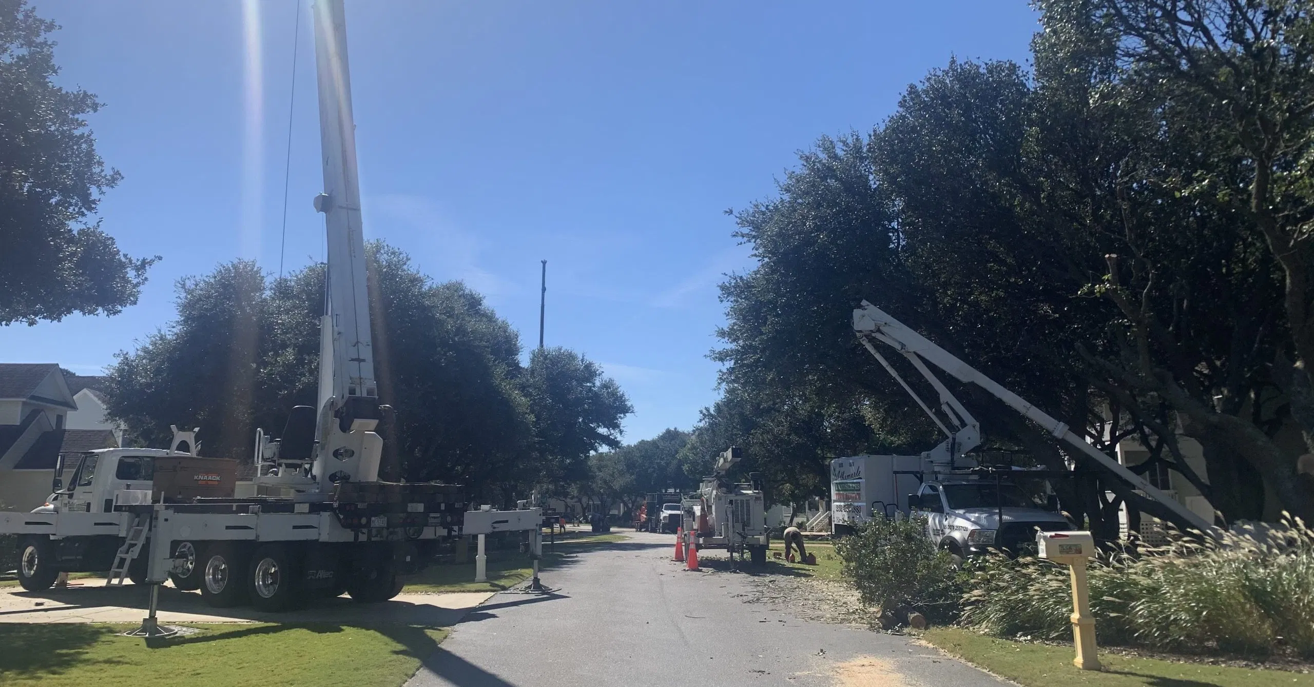 Side-by-side visual of a small boom truck setting rooftop HVAC equipment and a large crane placing bridge components, used to demonstrate scale and project suitability.